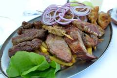 Various grilled meat on a metal plate on the table in the restaurant