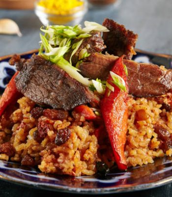 Pilau or Pilaf with Beef Meat Close Up Selective Focus. Traditional Asian Dish Plov also known as Polow, Pilav, Pallao, Pulao, Palaw with Rice, Spices, Vegetables and Fried Veal