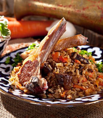 Pilaf - Rice with Lamb Chops and Vegetables. Garnished with Onions and Tomatoes Salad